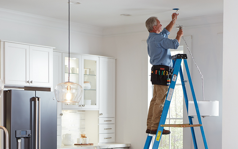 a man standing on a ladder connecting the mounting hardware