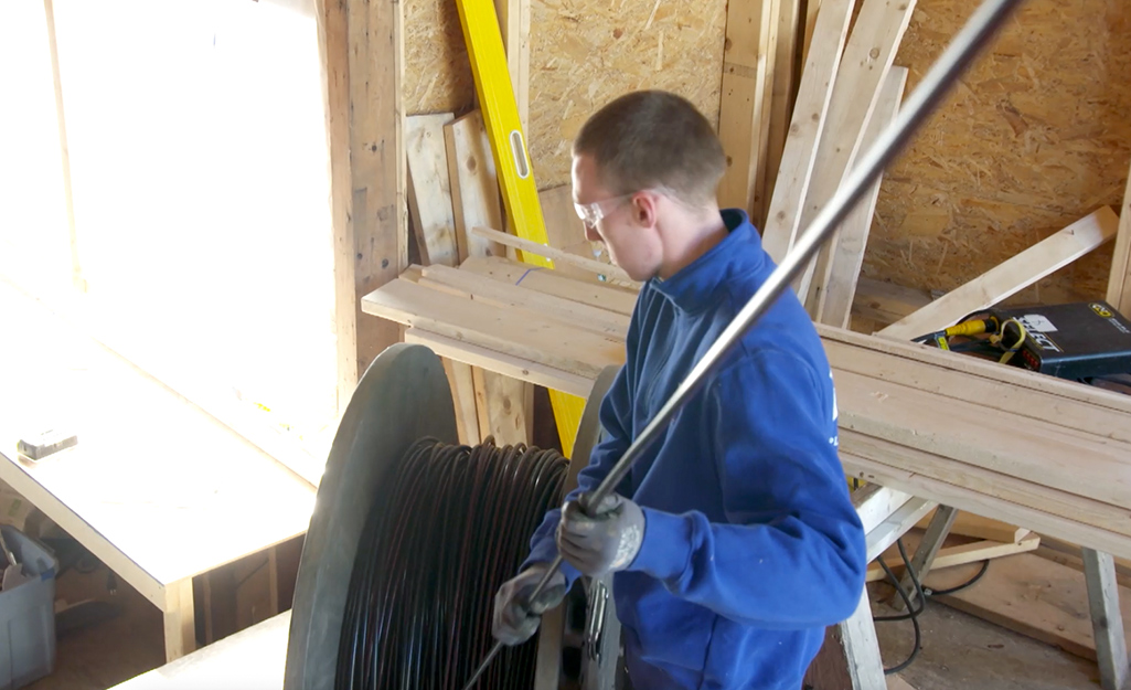 A person unspooling tubing for a heated floor installation.