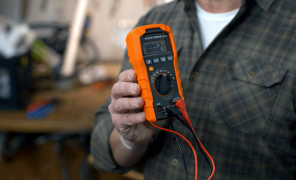 A person holding a digital multimeter.