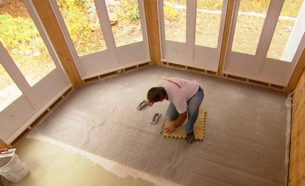 A person installing radiant flooring mat under flooring.