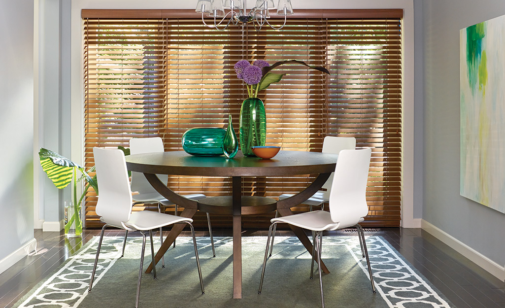 Wooden horizontal blinds cover French doors and windows in a dining room. 