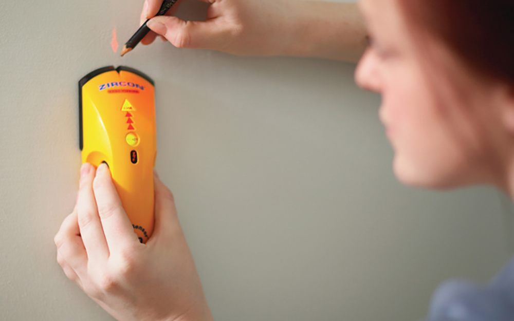 A stud finder being used to locate studs in a wall A stud finder being used to locate studs in a wall