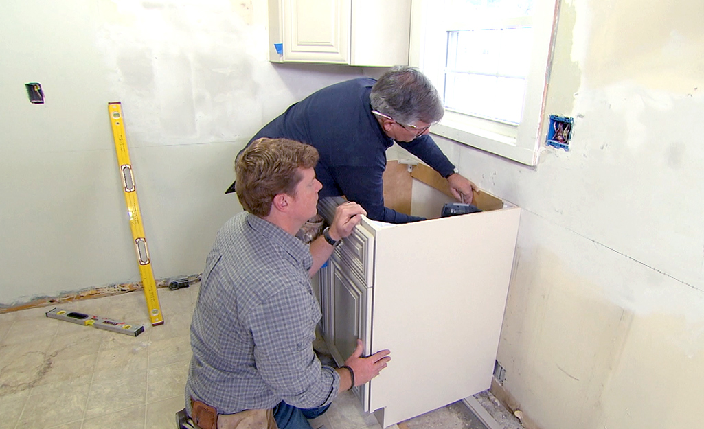 Two people installing a base cabinet.