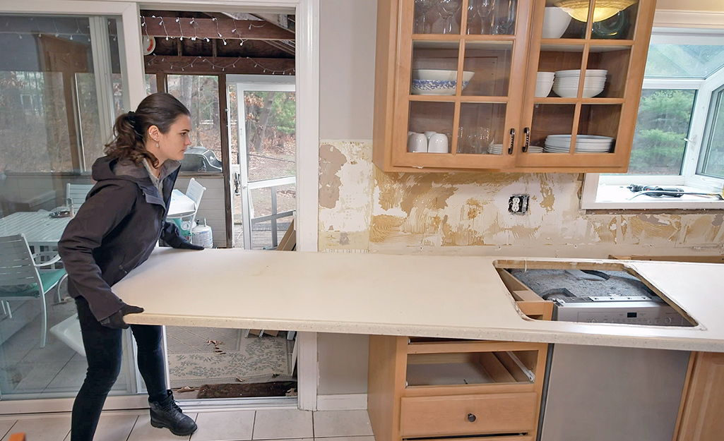 A woman helps to remove an old counter top.