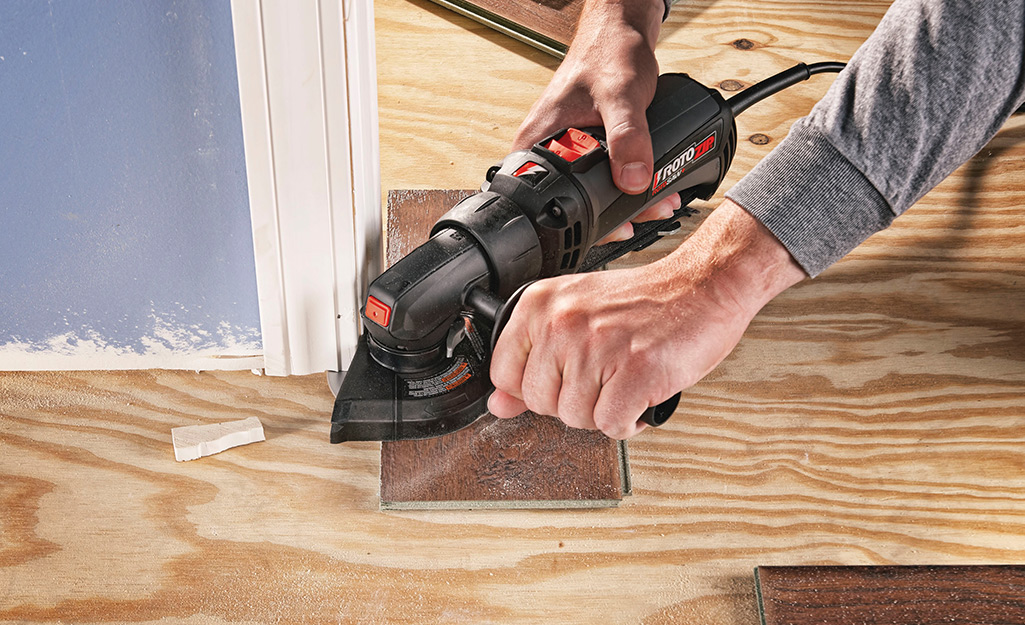 A man uses a saw to prepare door jambs for new flooring.