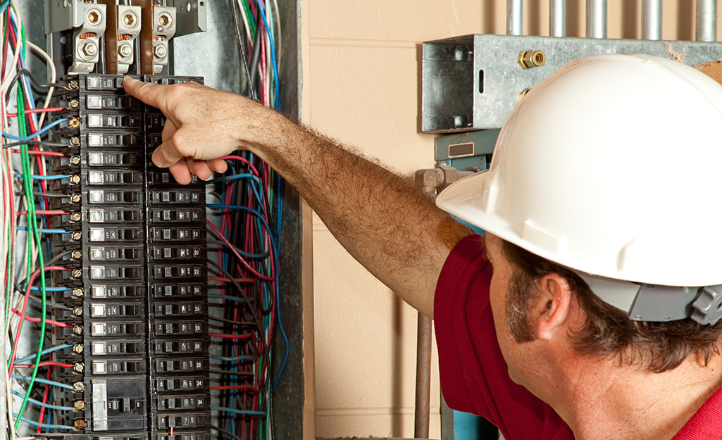 An electrician switching a circuit breaker in an electrical panel.