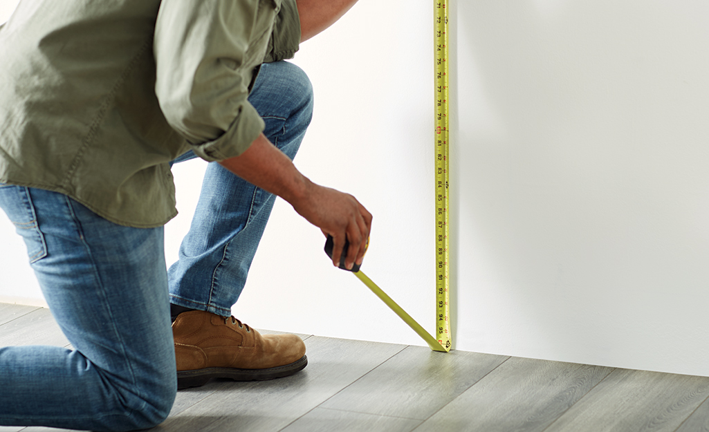 Someone measuring a wall from ceiling to floor