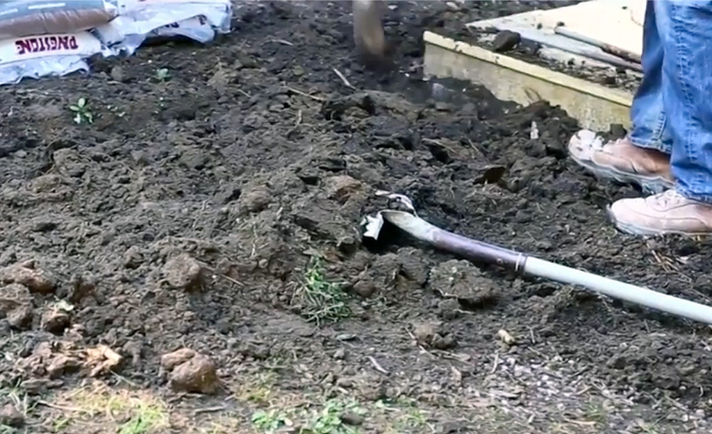 A person clears area with a shovel for a patio.