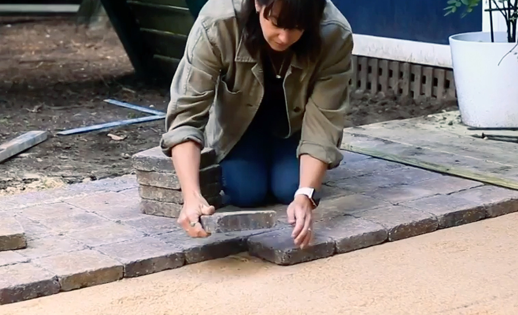 Brick pavers for a patio are installed atop tamped down sand.