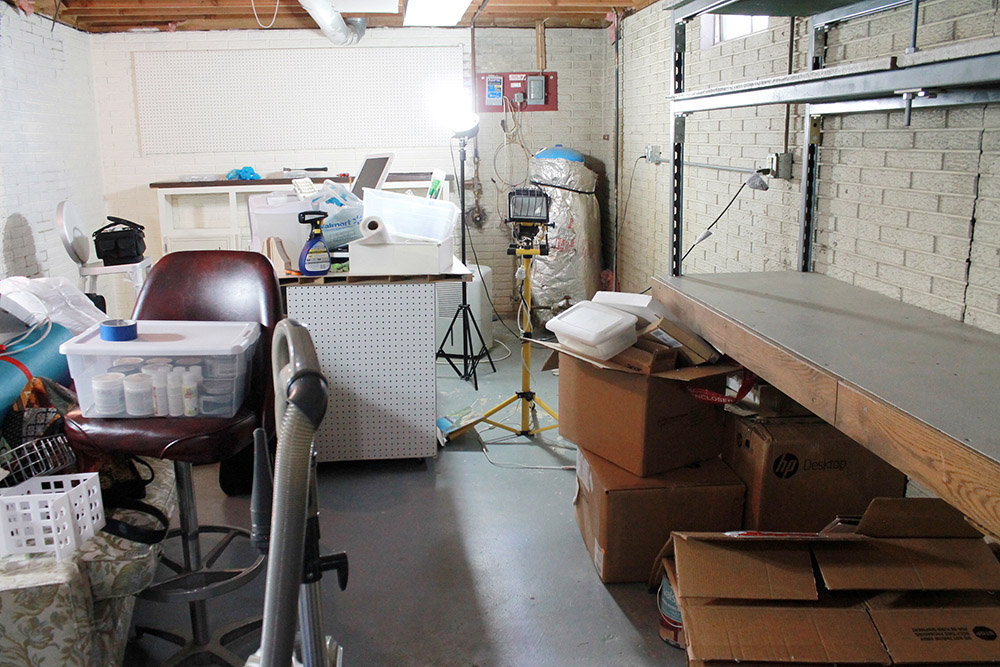 An unorganized basement with concrete floors.