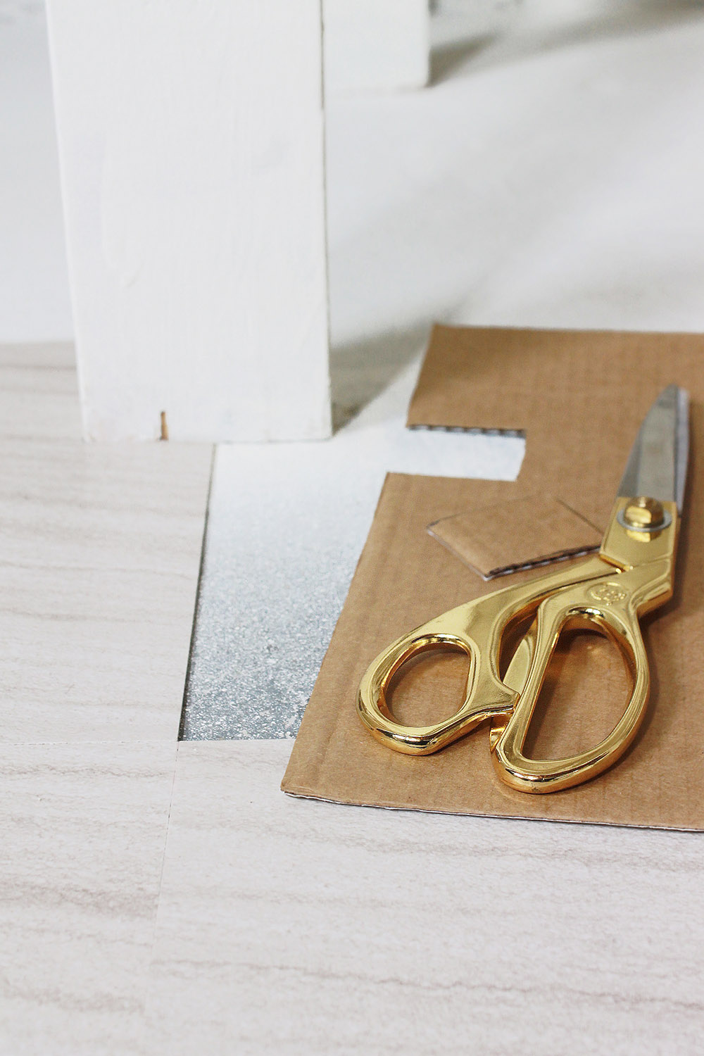 A piece of cardboard with a cutout creates a template for peel and stick tile flooring.