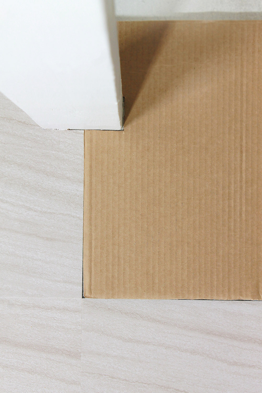 A piece of cardboard fits snugly against a wall post.