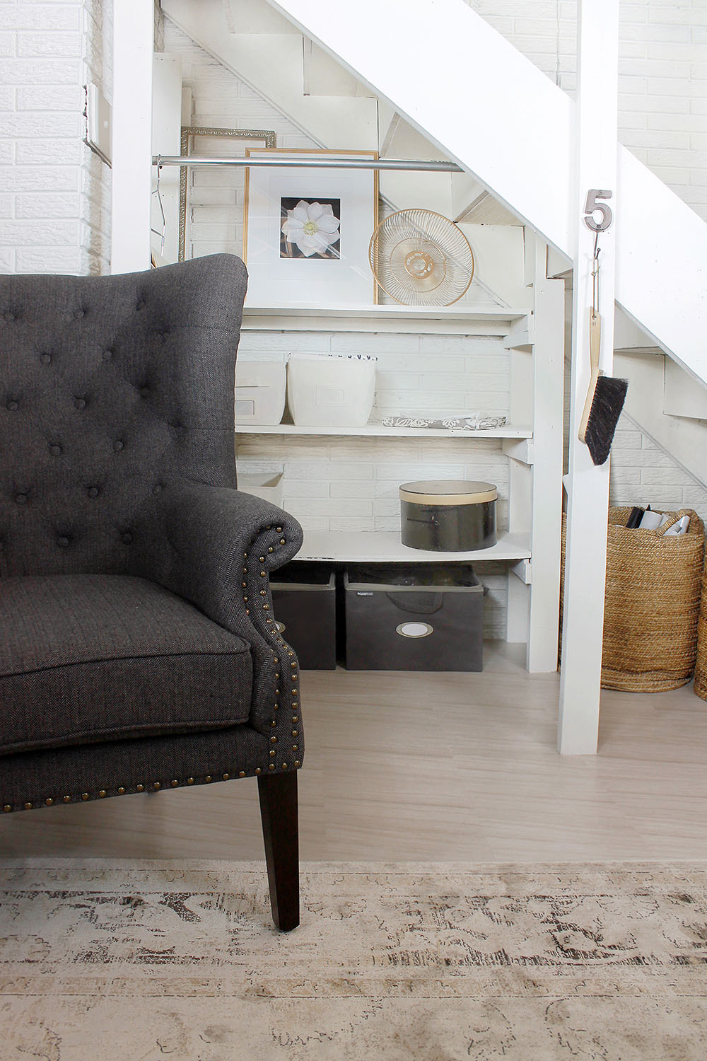 An accent chair sits on peel and stick tile flooring in front of a wall of decorated shelves.