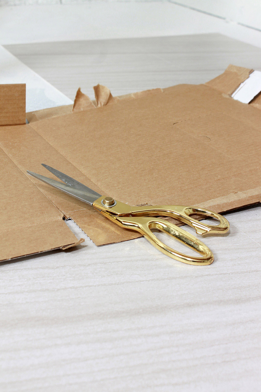 A pair of gold handled scissors on top of a piece of cardboard.