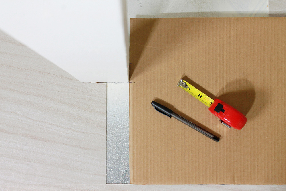 A pen and tape measure on top of a piece of cardboard.