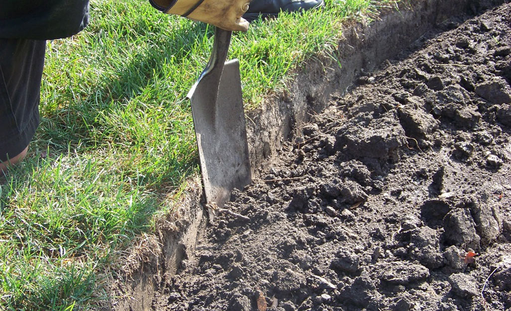 A person digging a trench for plastic edging.
