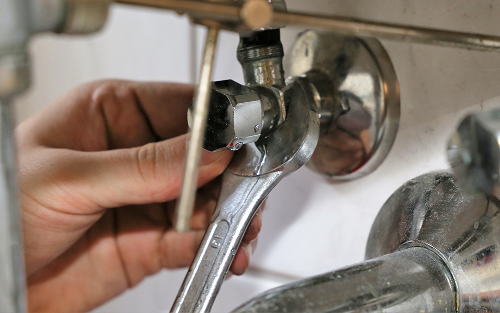 A person connecting a refrigerator water line.