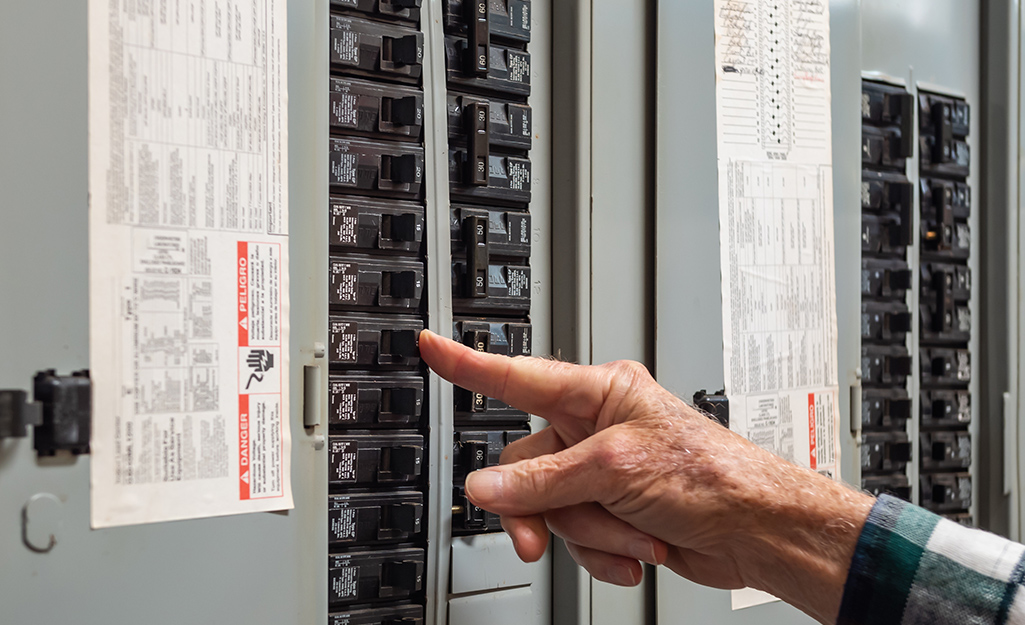 A person turning off a circuit breaker.