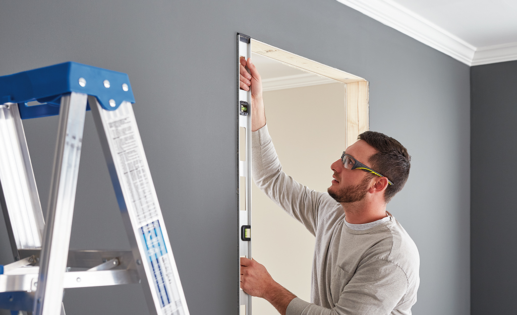 A man using a level to ensure a door frame is straight.