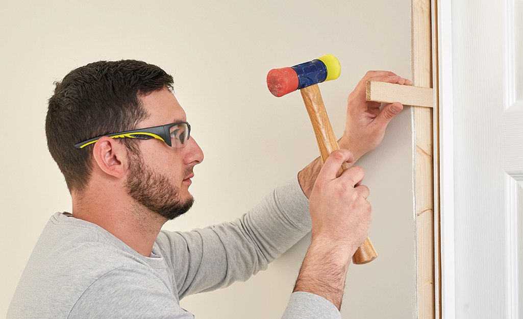 A man securing shims into the door frame.