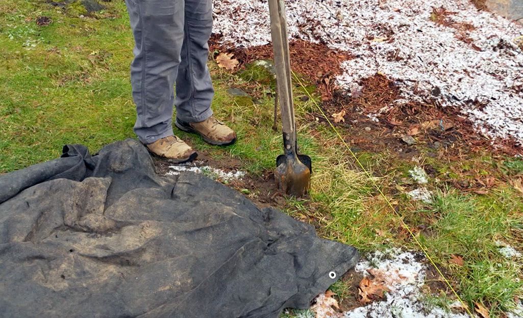 A person digging a post hole for a fence.