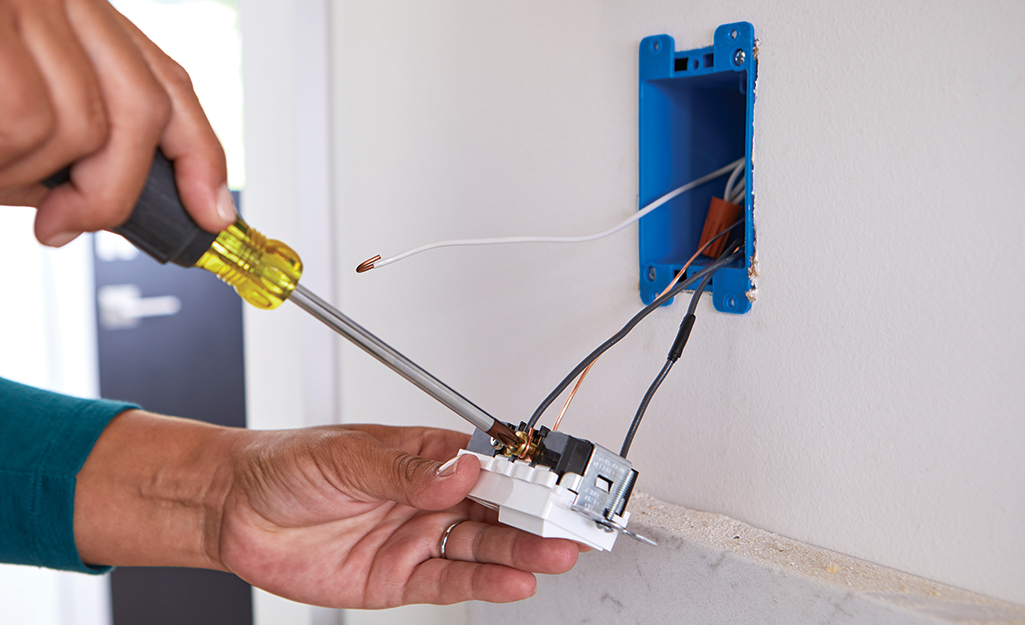 A person attaches wiring to a switch.