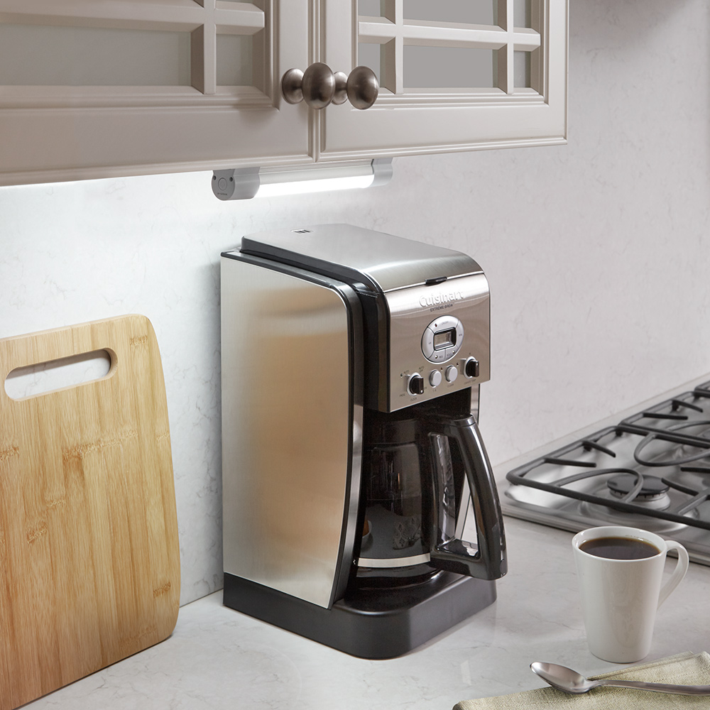 Undercabinet lighting highlights a coffee maker on a countertop.