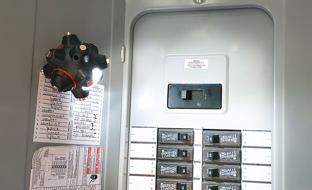 A open breaker box with a small light shining on the switches.
