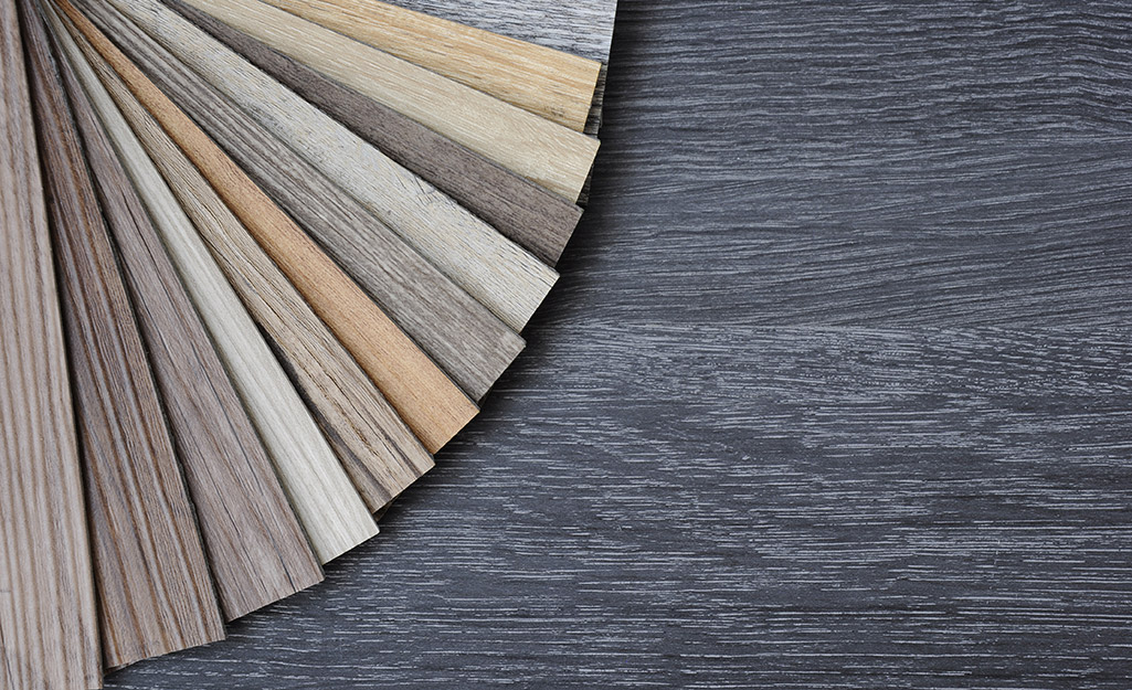 Different swatches of luxury vinyl plank flooring are fanned out over a vinyl floor.