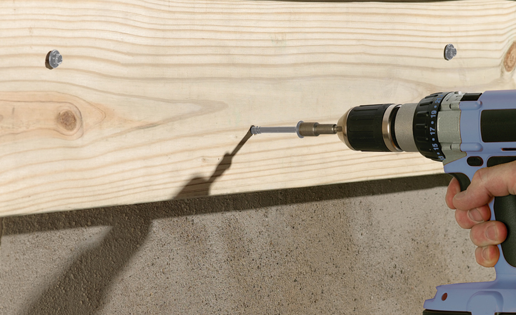 A person uses a drill to install screws.