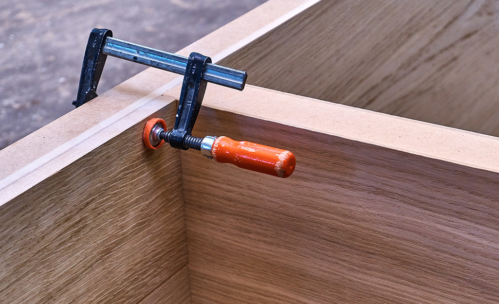 A clamp is used to hold wall cabinets together.