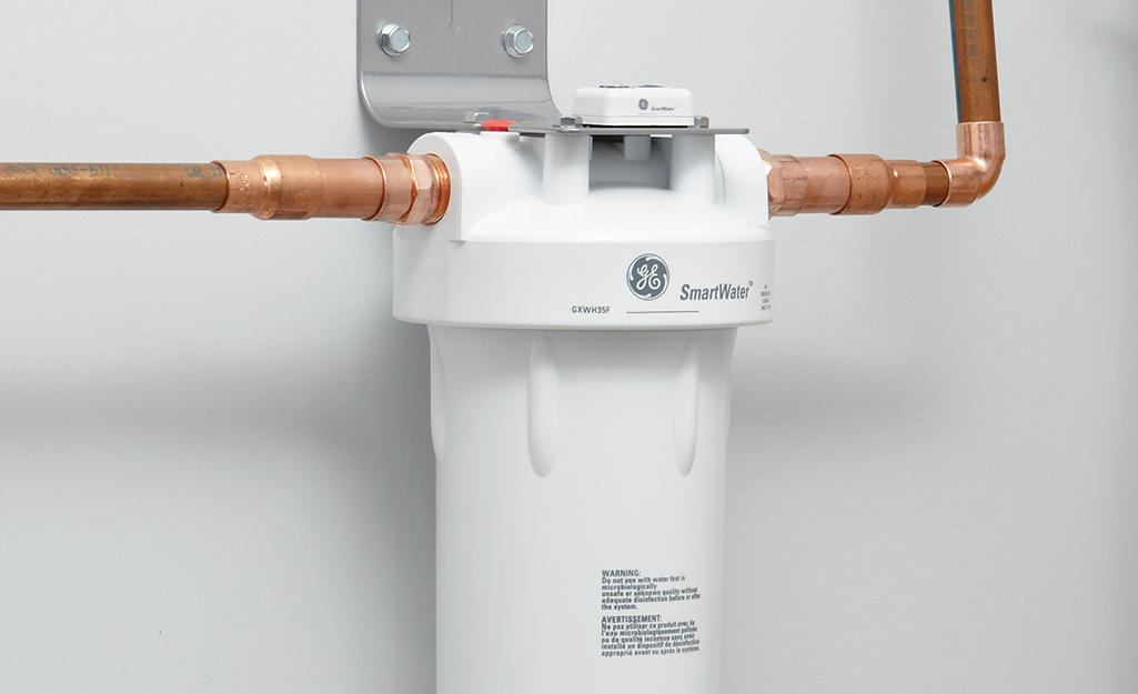 A whole house water filter attached to copper water supply pipes.