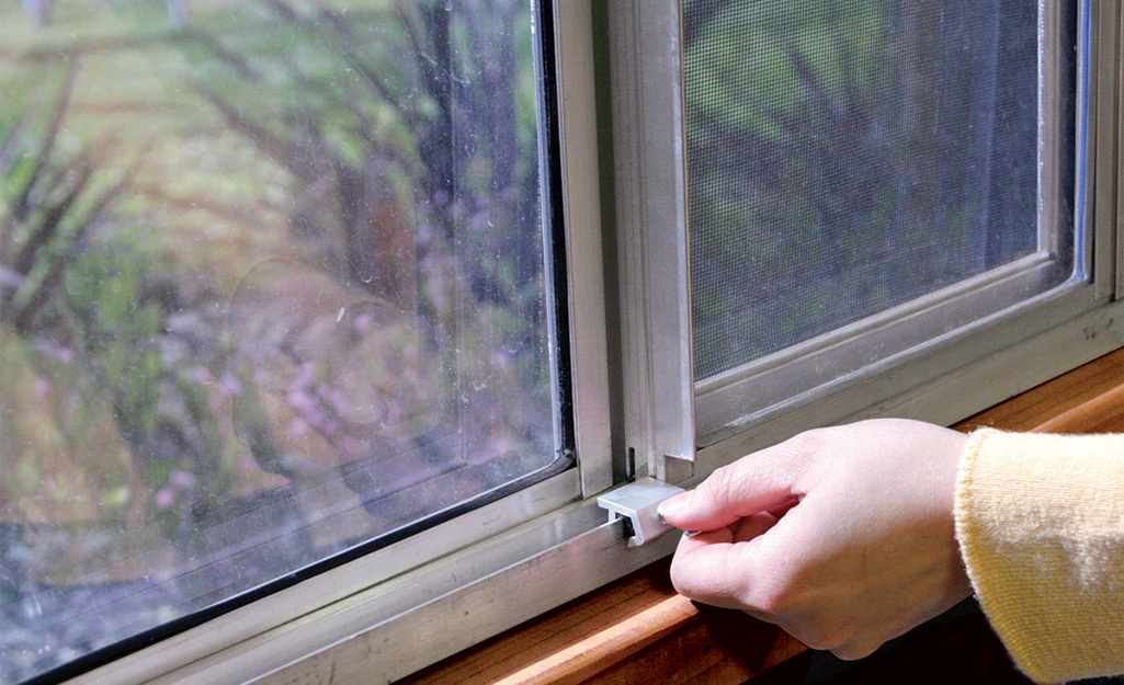 A person turns a key to lock a sliding window.