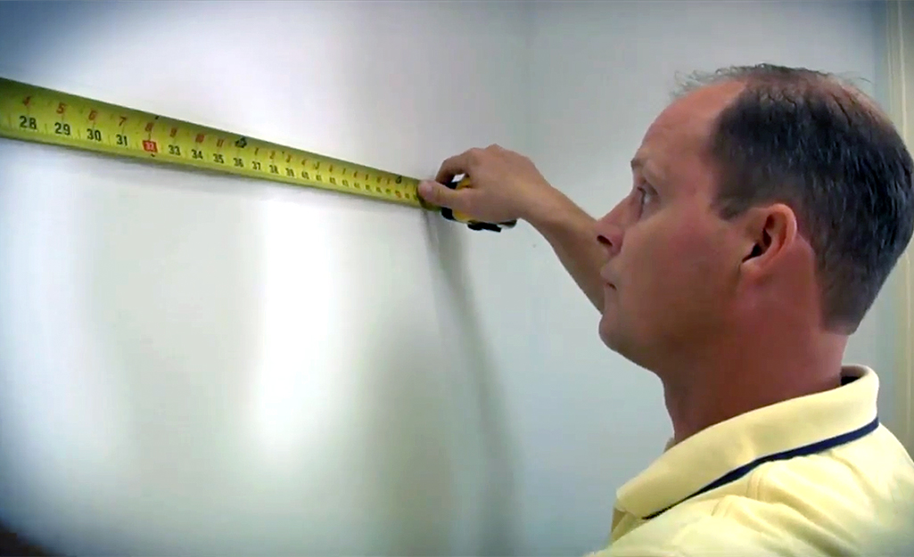 Man measuring wall in closet with a tape measure.