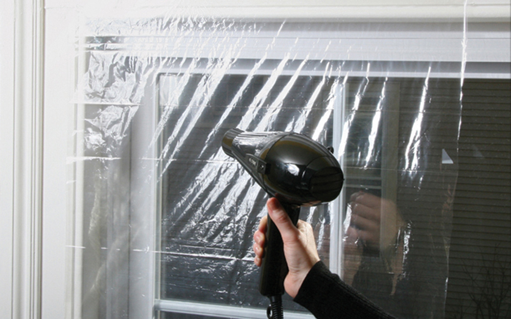 A hand drying window insulation plastic with a blow dryer.