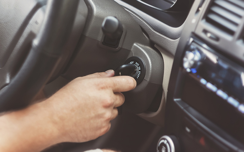 A person puts the key into the ignition of a car.