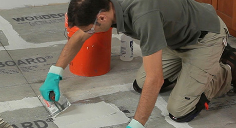 Man applying mortar using a square-notched trowel. Man applying mortar using a square-notched trowel.