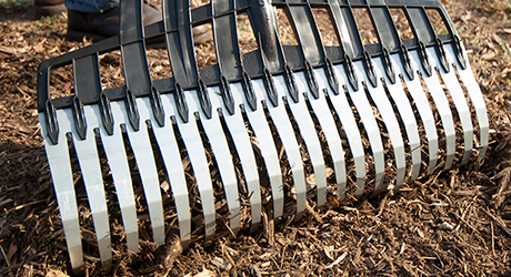 A large rake raking through soil. A large rake raking through soil.