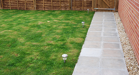 A lawn bordered by a paved patio. A lawn bordered by a paved patio.