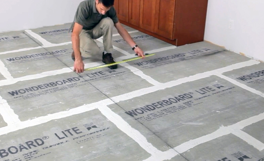 A man measures a floor for tile layout. 