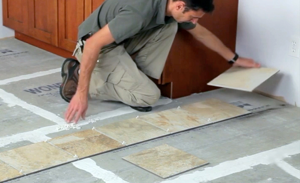 A man lays out floor tiles in sections.