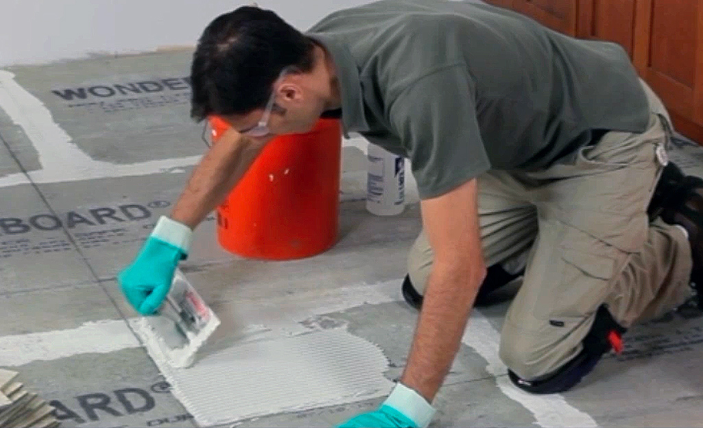 A person applies mortar to the floor.