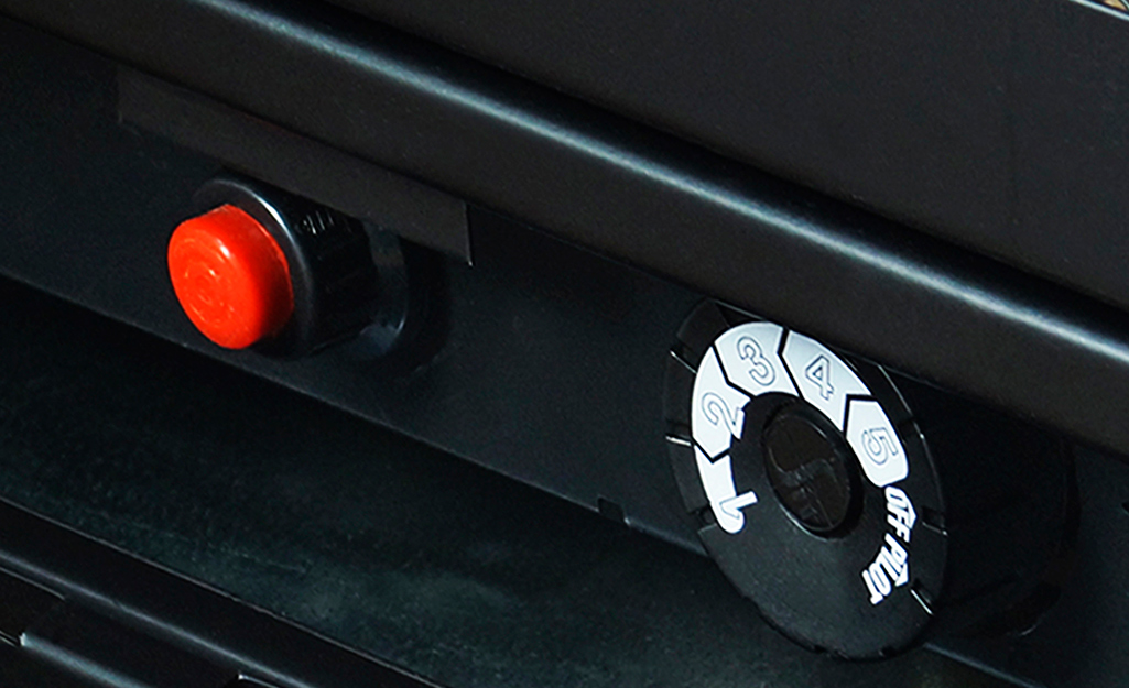 A gas fireplace control panel includes a red igniter knob and a control dial.
