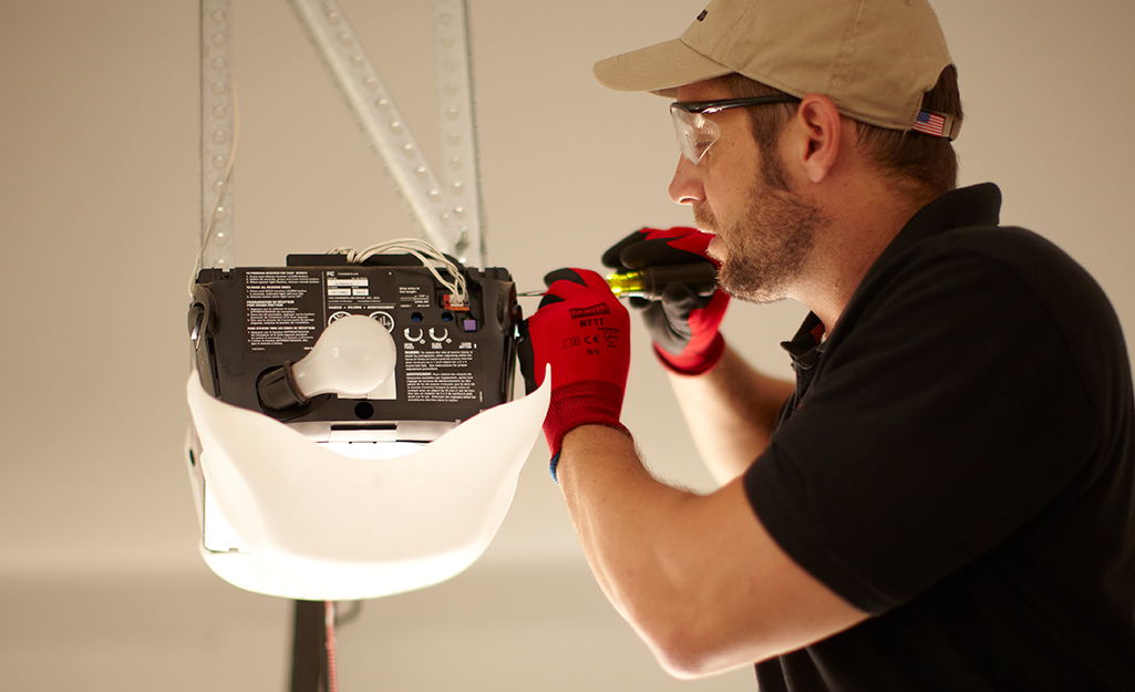 A person using a screw to adjust a garage door opener.