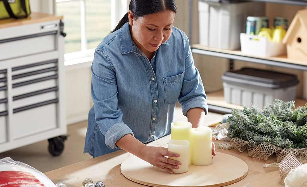 A woman arranging flameless candles in the middle of a wood board.
