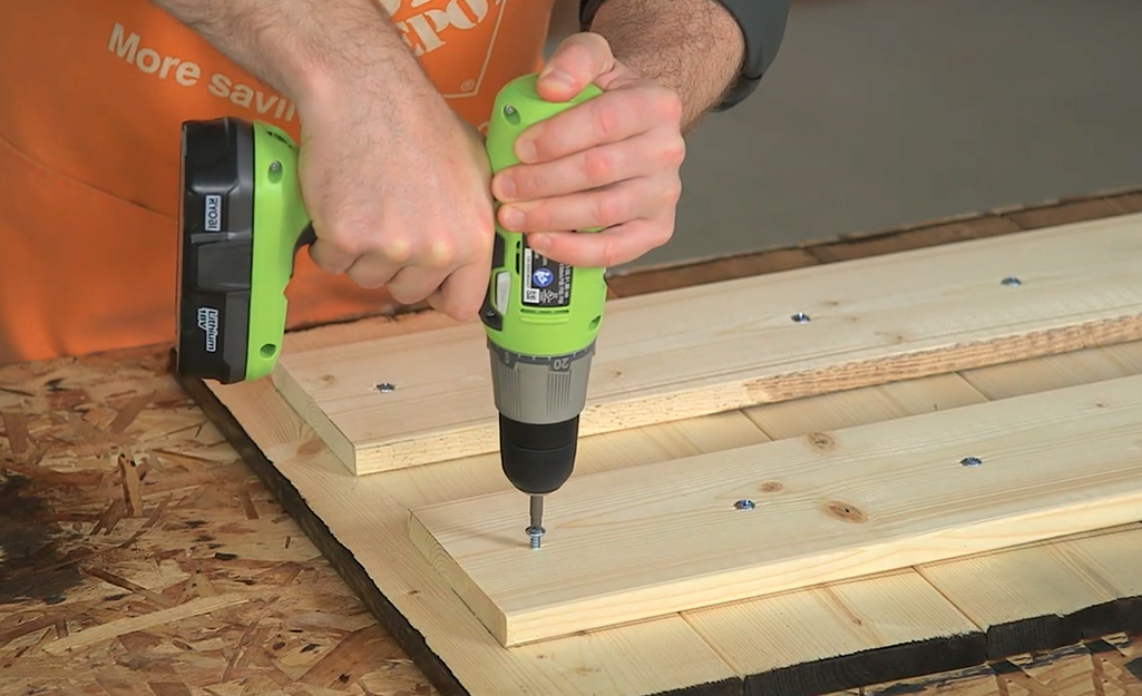 A person using a drill on a craft board.