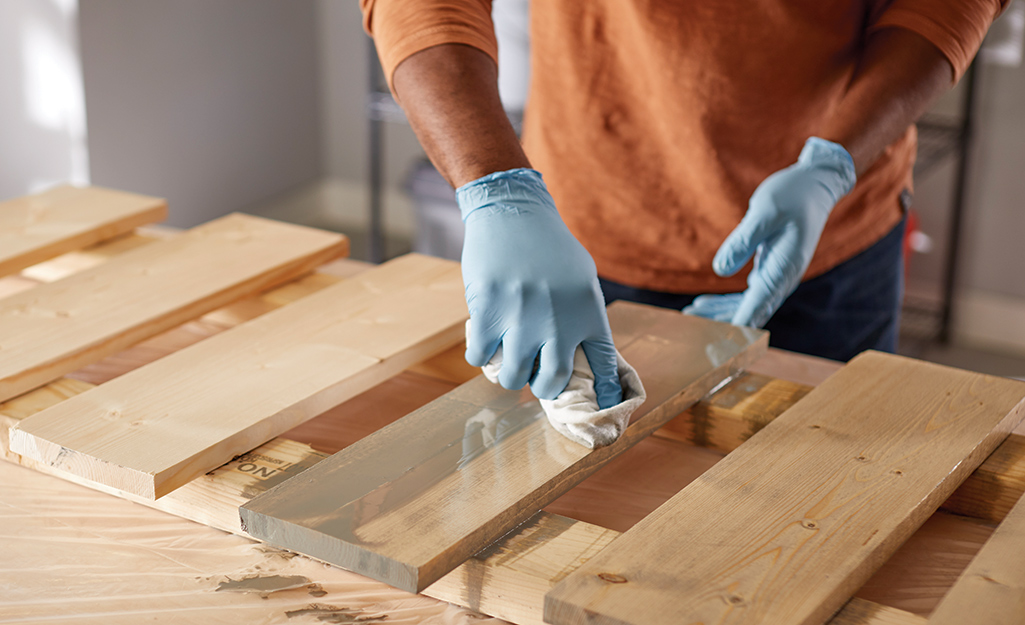 A person staining a board.