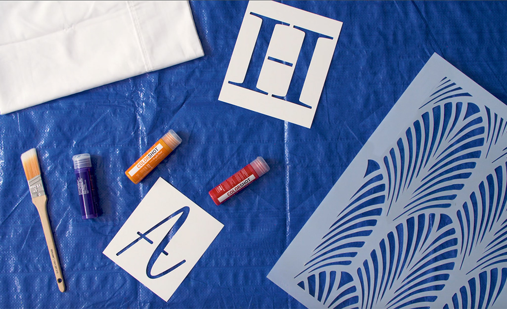 Stencils, paint, a pillowcase and paint brush lay on a tarp. Stencils, paint, a pillowcase and paint brush lay on a tarp.