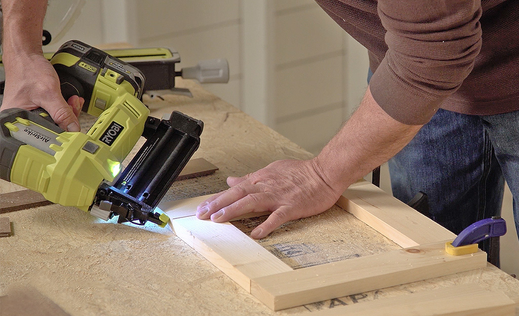 Person connecting wood pieces with nailer.