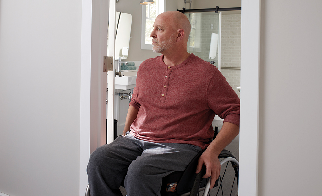 A man in a wheelchair in the doorway of an accessible bathroom.